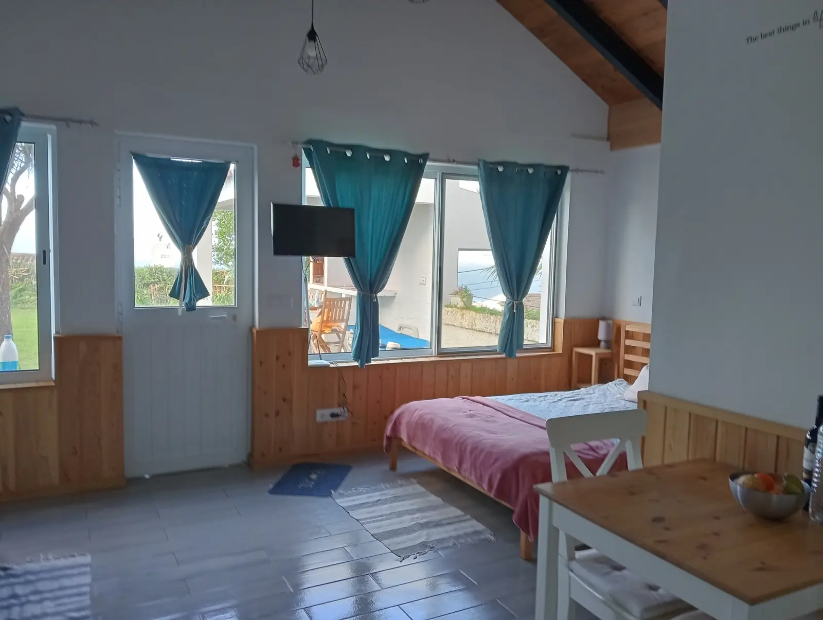 Schlafbereich mit Doppelbett und Fenstern zur Terrasse